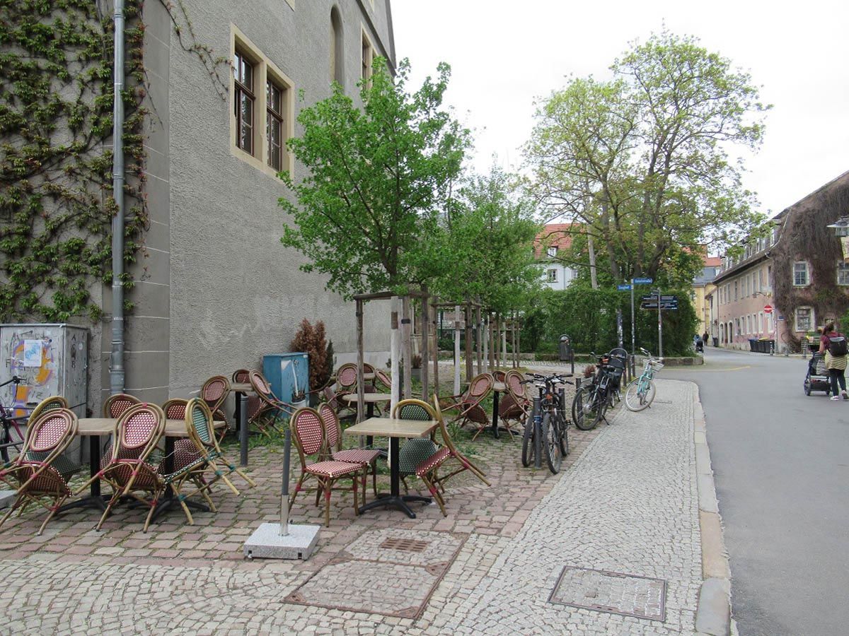städtischer Platz mit Außengastronomie, neu gepflanzten Bäumen und Pflasterstraße